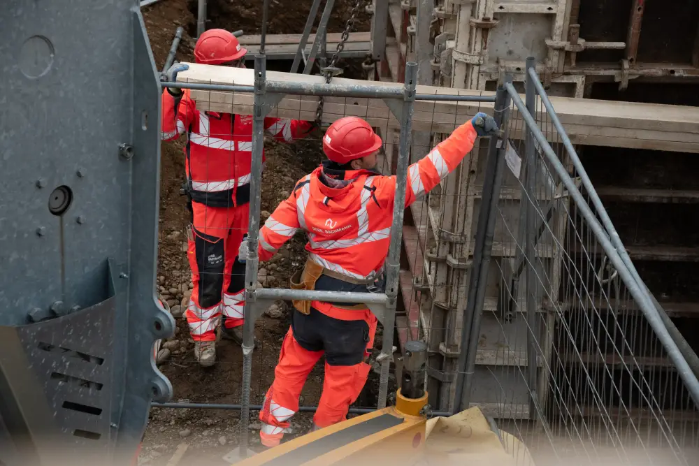 Zwei Mitarbeiter am Rand einer gesicherten Baugrube