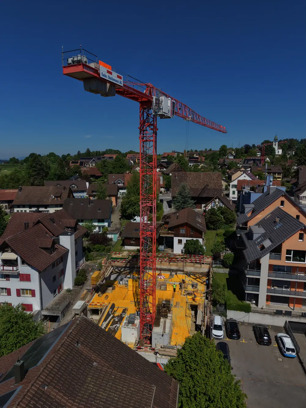 Roter Turmdrehkran über einer Rohbaustelle mitten im Wohnquartier