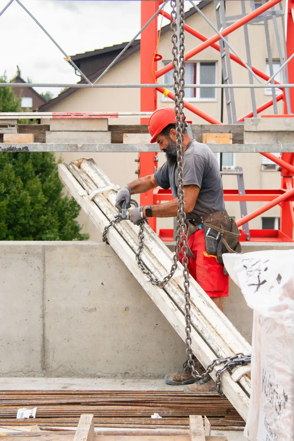 Mitarbeiter hängt ein Betonelement an die Kranketten