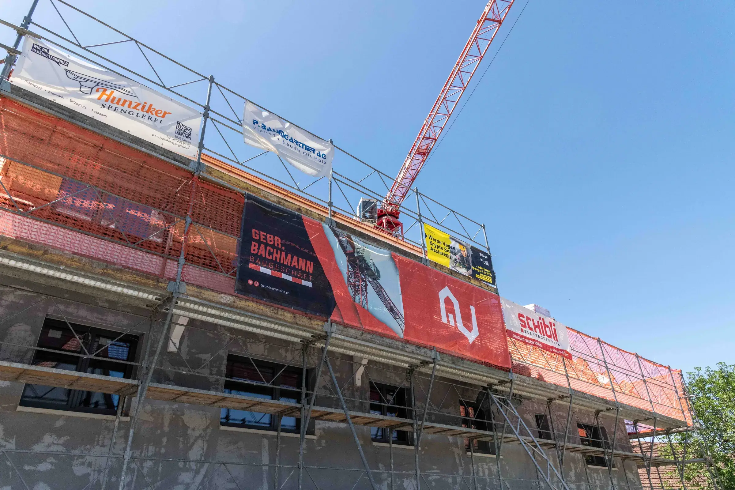 Eingerüstete Fassade mit Baubanner der Gebr. Bachmann AG und Baukran